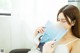 A woman in a white dress reading a magazine.