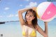 A woman in a yellow bikini holding a beach ball.