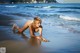 A woman in a white bikini laying on the beach.