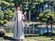 A woman in a white dress standing in front of a pond.