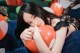 A woman laying on a bed holding a bunch of balloons.