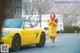 A woman in a yellow coat is walking down the street next to a yellow car.