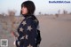 A woman standing in the middle of a desert.