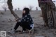 A woman sitting on the ground next to a tree.