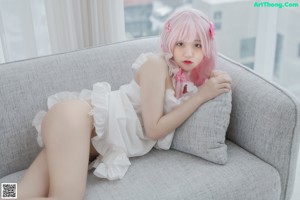A woman with pink hair is sitting on a couch.