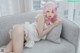 A woman with pink hair is sitting on a couch.