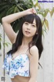 A woman in a blue and white floral top posing for a picture.