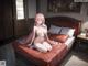 A naked anime girl sitting on a bed in a bedroom.